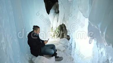 人类在一个冰洞里用智能手机交流。 围绕着神秘美丽的冰窟.. 用户在社交中交流